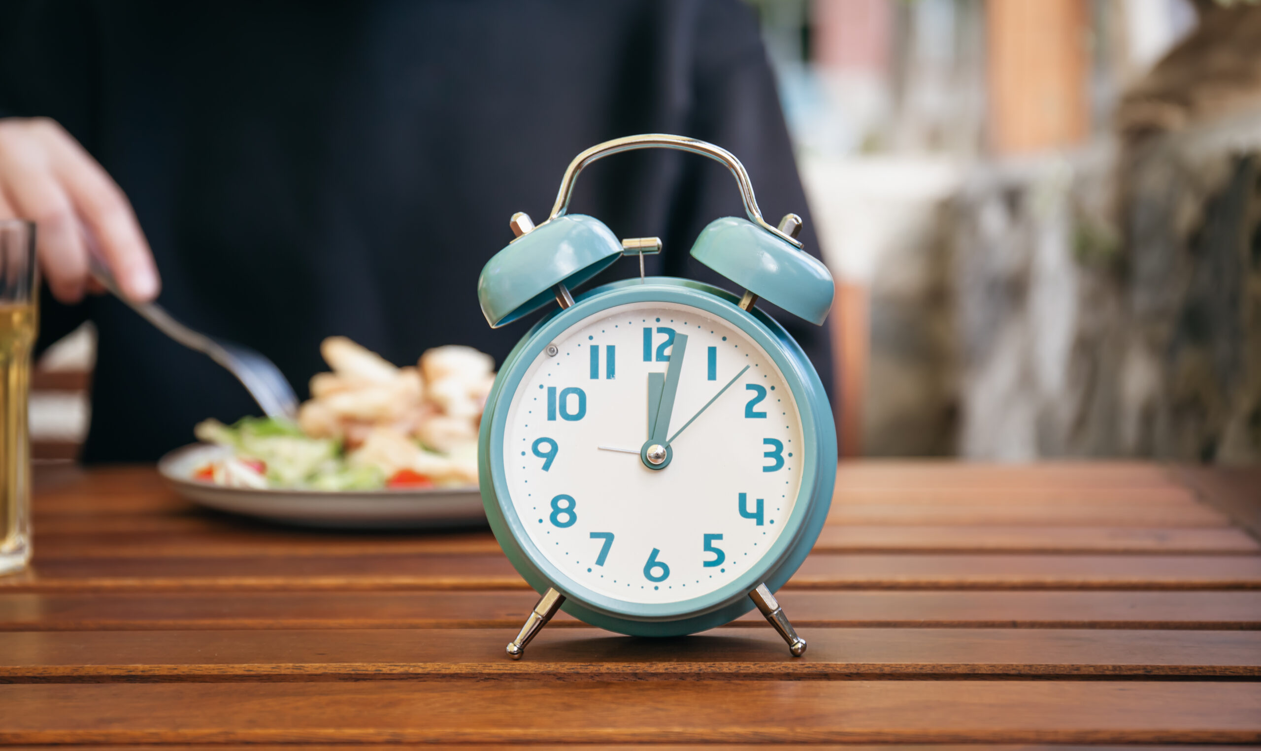 Close-up, alarm clock on a blurred food background.